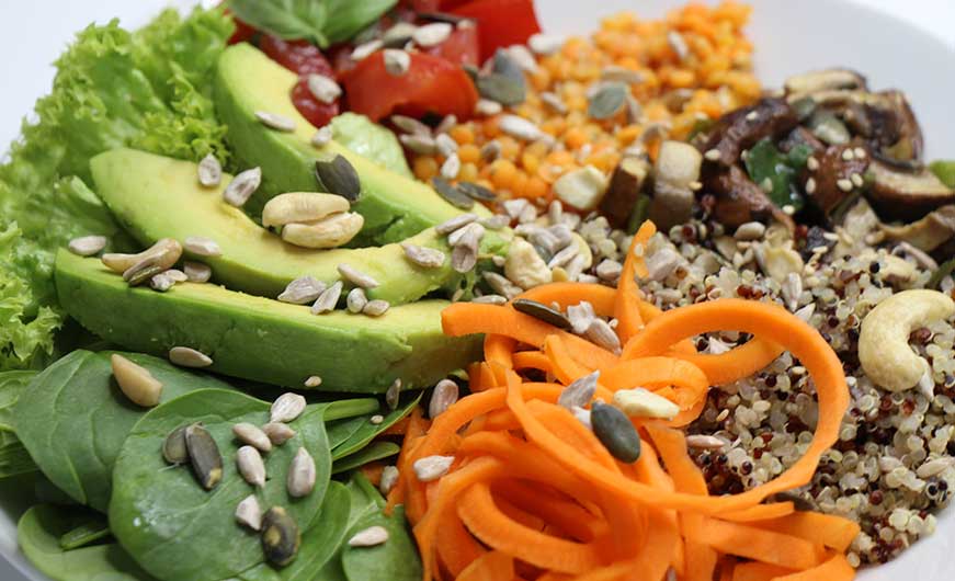 Bowl vegan Nahaufnahme mit Avocado Karotten Babyspinat und mehr