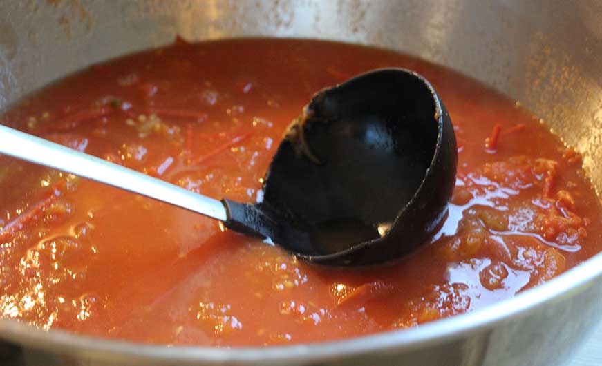 schuessel mit gekochten frischen tomaten mit schoepfloeffel